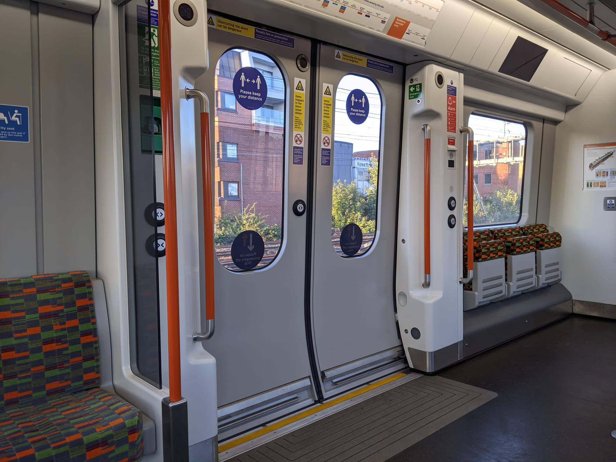 On the inside, the doors are coloured grey. There are bright orange handrails either side of the door. Next to them are door control buttons. Above the door is a map of the network.