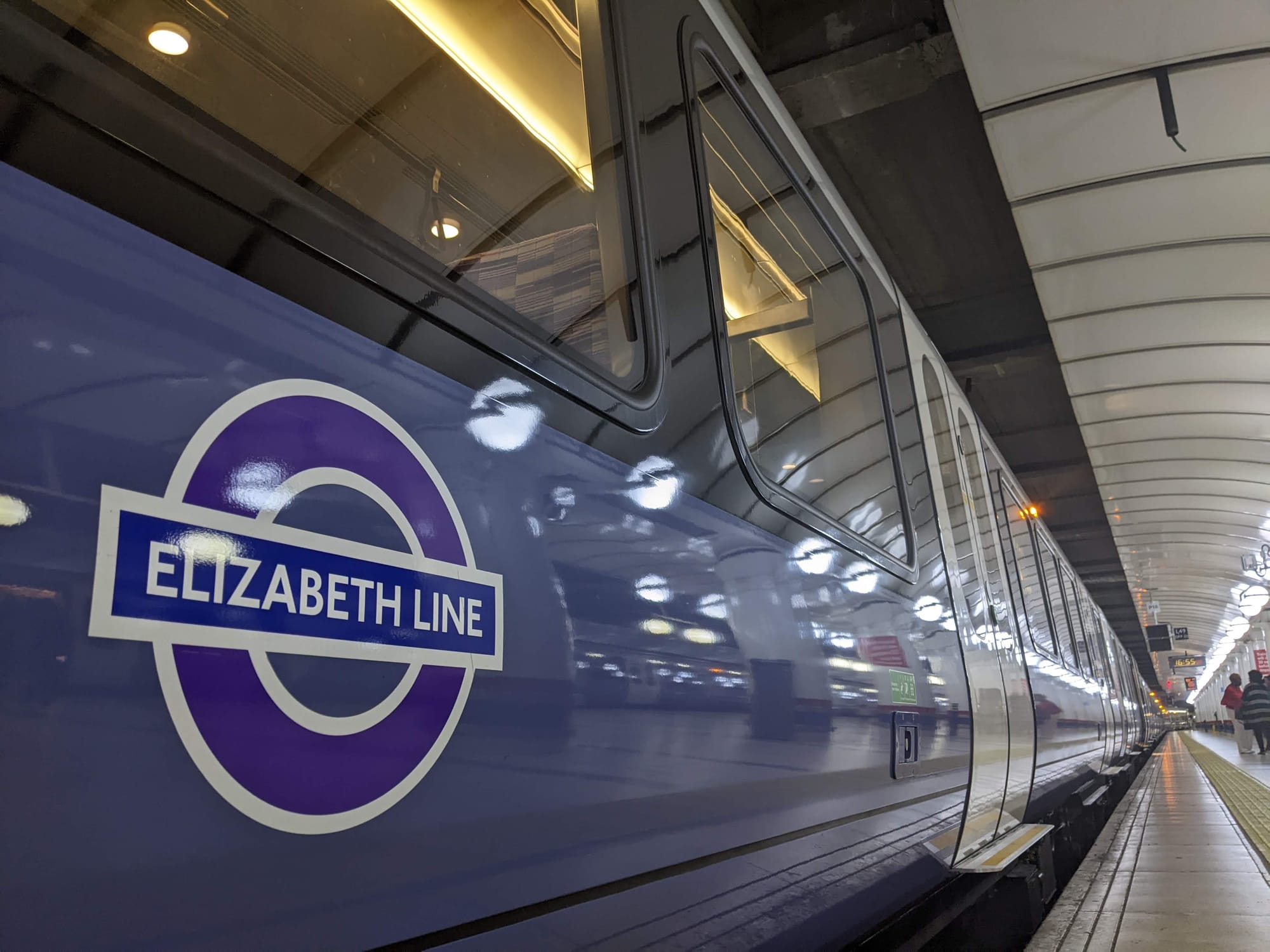 A close-up of the side of an Elizabeth line train, which bears a deep purple roundel with 'Elizabeth line' across the centre in white font.