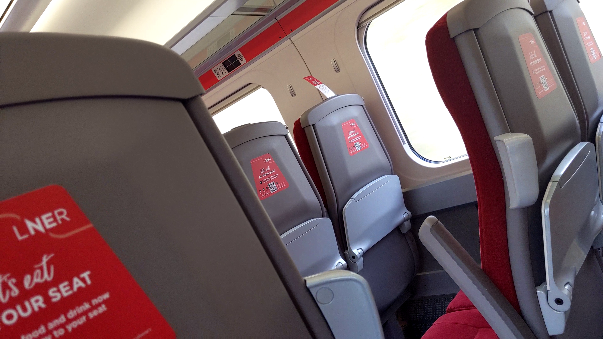 Seats in standard class are plastic on the back with a deep red moquette. On the backs of the airline-style seats are fold-down tables that could hold a few small items. Above seats are glass luggage racks which you can see through.