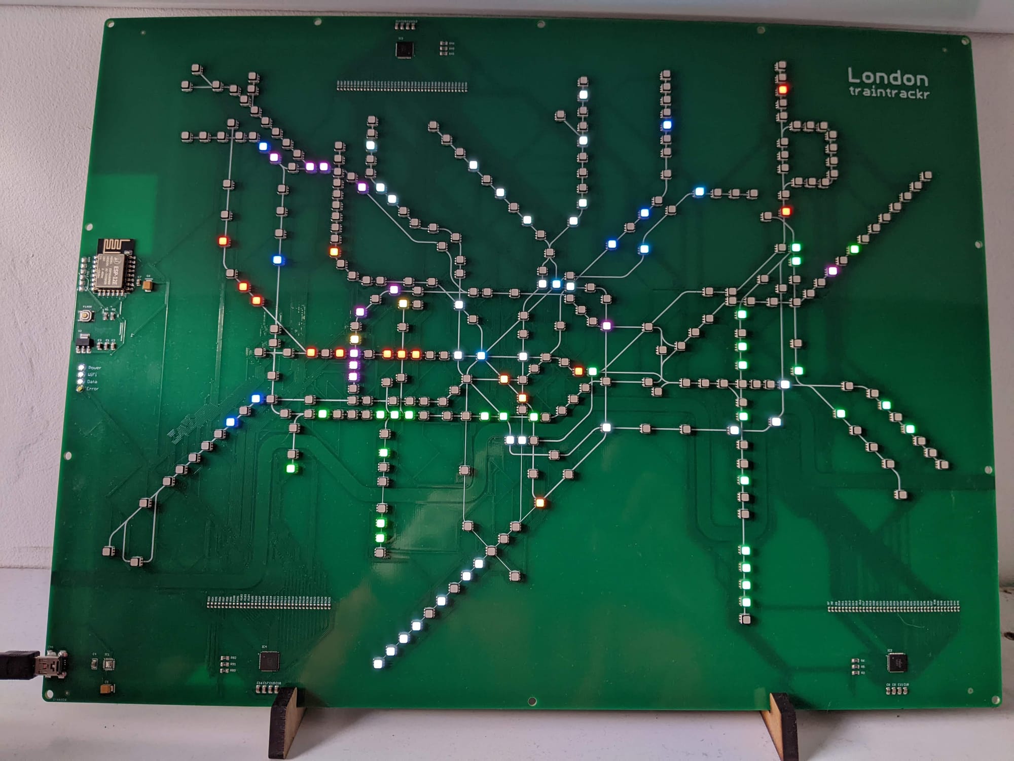 Small LED modules are arranged in the shape of the London Underground map on a green circuitboard. Thin white lines have been printed on the board to represent the tracks.