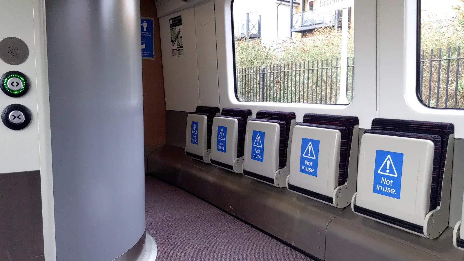 On the left are buttons to open and close the accessible toilet door, with a speaker above them. On the right are tip-up seats.