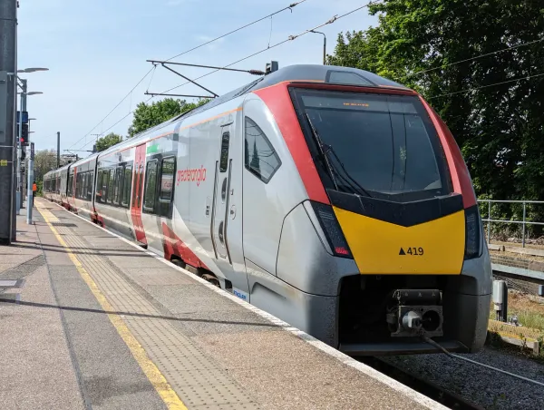 A Class 745 train is stationary at Ipswich station. The front is yellow and red. It is in a white Greater Anglia livery.