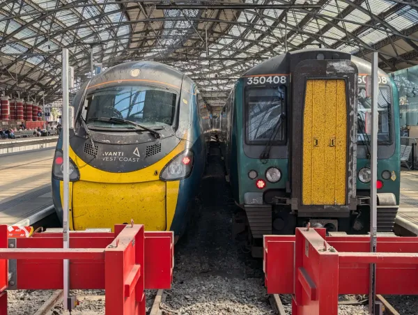 Two trains are stationery in front of the buffers at Liverpool Lime Street station. There is a Class 390 and Class 350.