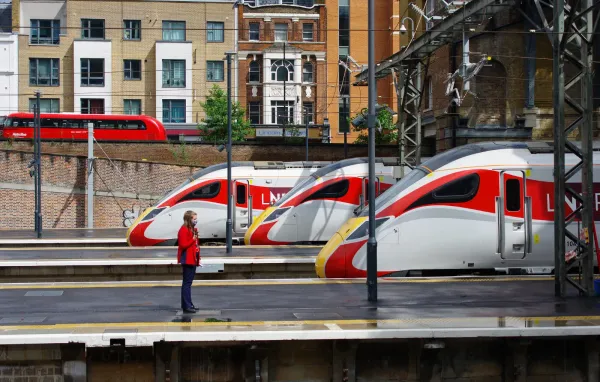 Three LNER Azuma trains in their white and red liveries wait at adjacent platforms at King's Cross station in London.