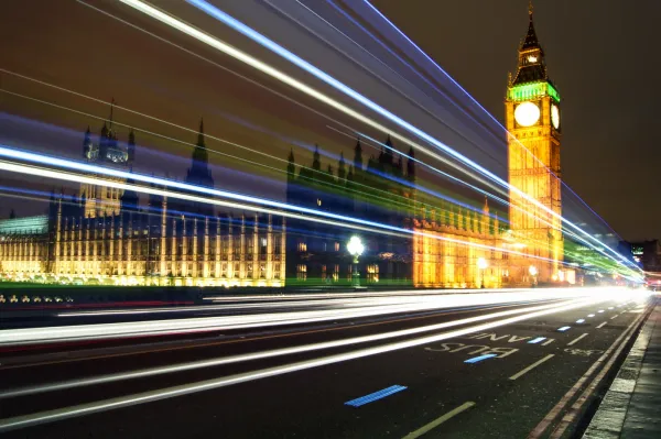 A long exposure photo of the Palace of Westminster's exterior. Streaks of vehicles' lights illuminate Westminster Bridge.