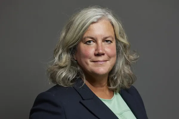 Heidi Alexander stands in front of a grey background for her official portrait.