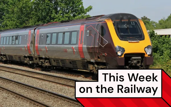 A train runs at speed along a mainline. It has a maroon and grey livery, with bright pink doors and a yellow front.