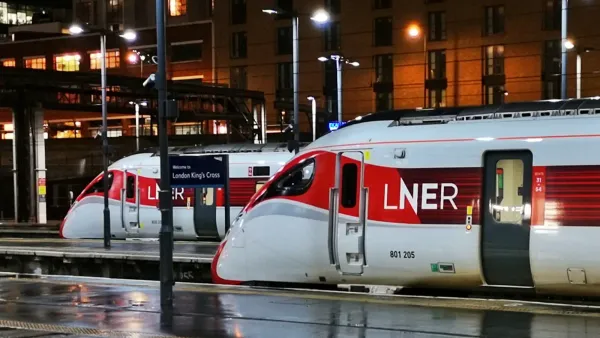 Two LNER Azuma trains in their red and white liveries are stationary on adjacent platforms at London's Kings Cross Station.